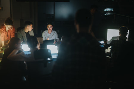 Business coworkers collaborating on a project in a dimly lit officeの写真素材