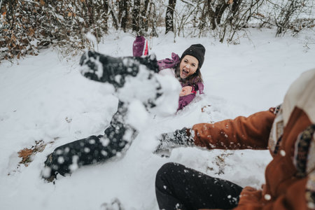 Friends enjoying a playful snow day outdoors surrounded by natureの写真素材