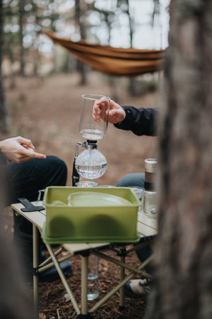 Outdoor Setup Featuring a Siphon Coffee Maker on a Picnic Table in a Natural Forest Settingの写真素材
