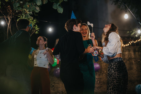 Friends celebrating together outdoors with decorations and warm lightingの写真素材