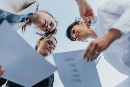 Group of female freelance entrepreneurs reviewing important documents outdoors in collaborationの写真素材