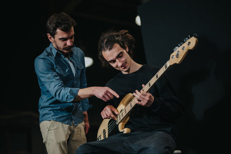 Two individuals are engaged in a music session, one teaching guitar techniques to the other, promoting education and creative expression.の写真素材