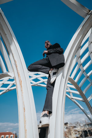 Businessman balancing on a modern structure under a clear blue skyの写真素材