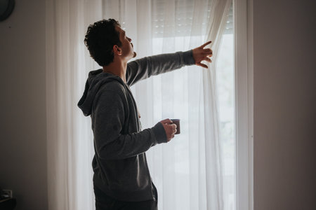 Young man enjoying morning light while holding a cup of coffeeの写真素材