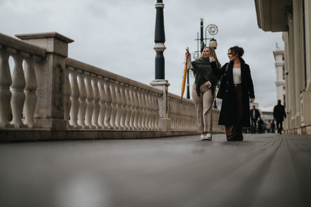 Two friends walking along a city promenade on a cloudy day outdoorsの写真素材
