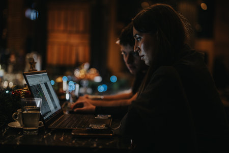 Young professionals collaborating on a project in a cozy cafe settingの写真素材