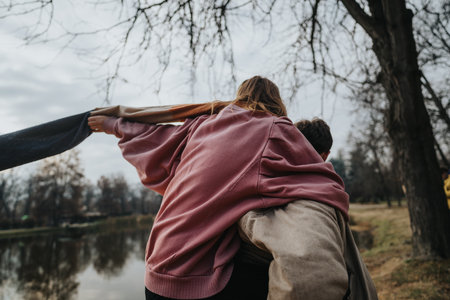 Friends enjoying outdoors during autumn by a tranquil lakeの写真素材