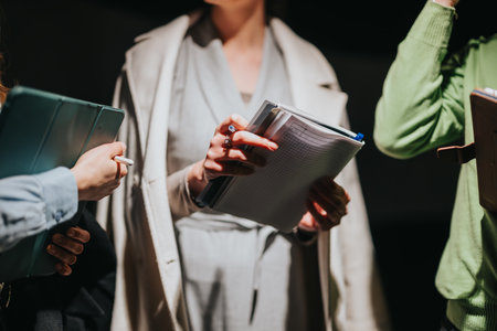 People engaging in discussion during an event, holding documents and attentively participating