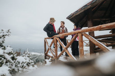 Friends enjoying a winter day together near a wooden cabin in the snowy mountainsの写真素材