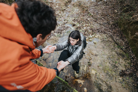 Hiker helping another across a rocky creek in a forest setting