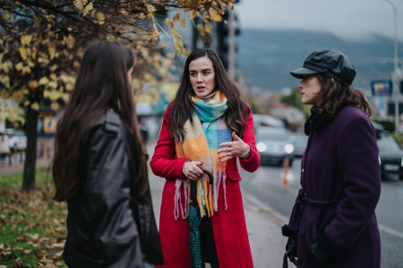 Three women interacting in a city street scape on a cloudy dayの写真素材