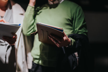 Two people examining notebooks during a museum visit under soft dramatic lighting