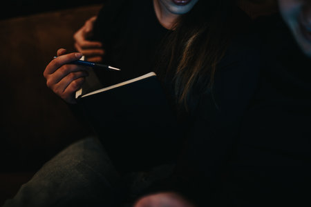 Close-up of hands holding a pen and a black notebook during planningの写真素材