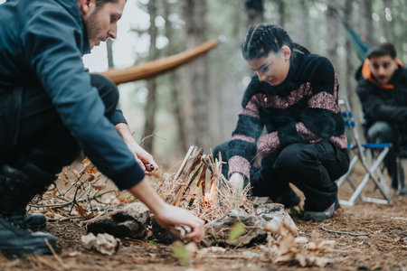 Friends gather outdoors, building a small campfire in a scenic forest