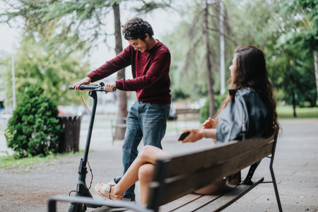 Young man showcasing electric scooter to female friend in park