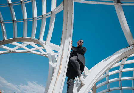 Confident man outdoors near a modern architectural structure with blue sky