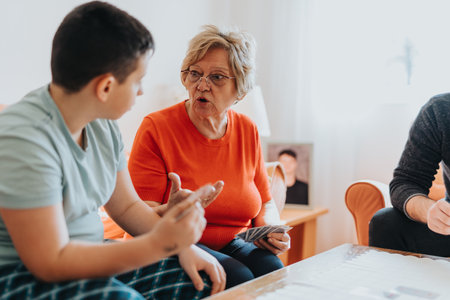 Elderly woman playing cards with family while engaging in meaningful discussionの写真素材