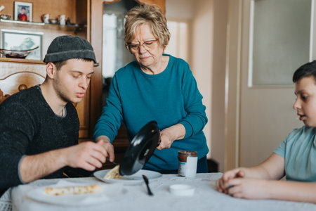 Senior woman assisting young adults with mealtime preparation at a family tableの写真素材