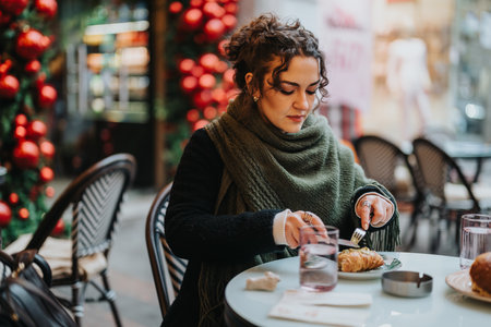 Woman Enjoying Holiday Breakfast in an Outdoor Cafe with Festive Decorationsの写真素材
