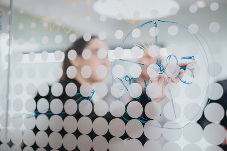 Business people collaborating and brainstorming ideas on a transparent board in a modern office settingの写真素材