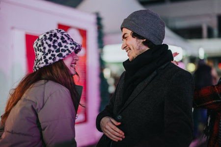 Friends laughing outdoors together during a cold winter eveningの写真素材