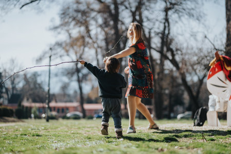 Woman and child playing together outdoors in a sunny parkの写真素材