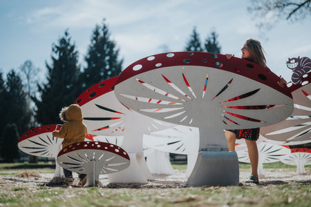 Family enjoying playful wooden mushroom sculptures in an open parkの写真素材