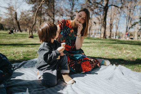 Mother and child sharing a delightful picnic moment outdoors on a sunny dayの写真素材