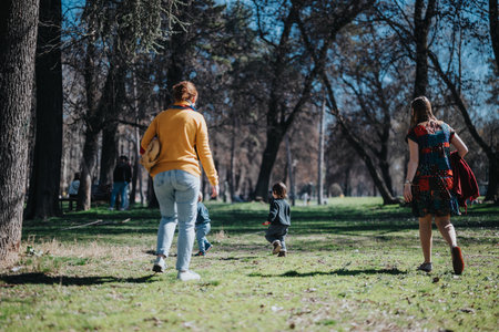 Family enjoying a sunny day in a park surrounded by treesの写真素材
