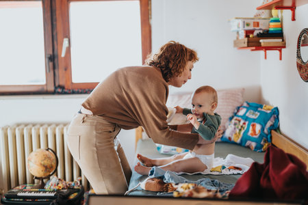 Mother assisting playful baby during diaper change in cozy home setting