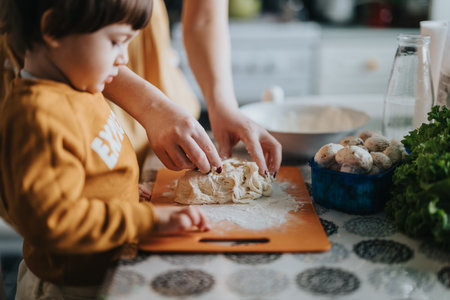 Parent and child working together to prepare dough for cooking in a cozy kitchenの写真素材