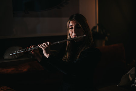 Young woman playing flute in a warmly lit cozy interior setting