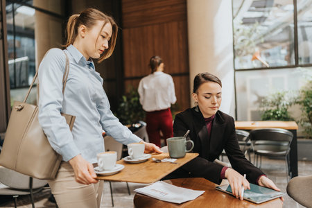 Colleague interactions in a coffee shop setting discussing business with beverages and devices.