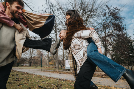 Friends playing joyfully outdoors during a crisp autumn afternoonの写真素材