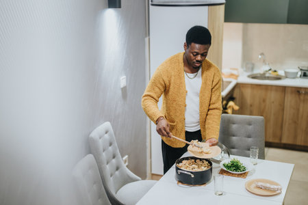 Man serving a meal at home in a cozy kitchen with a stylish interior designの写真素材