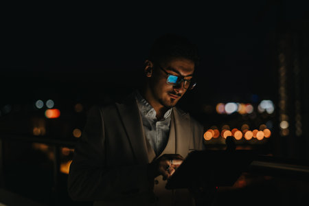 Business professional working late at night on a tablet outdoorsの写真素材