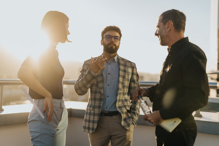 Three business colleagues engage in a lively discussion on a high tower balcony.の写真素材
