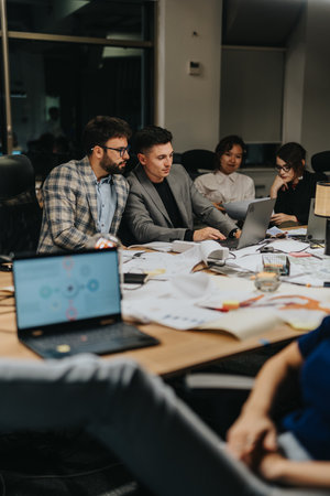 A team of business people working late into the night in an office environment, collaborating on project deadline.の写真素材