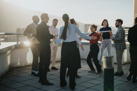 Diverse colleagues celebrating on rooftop during golden sunsetの写真素材
