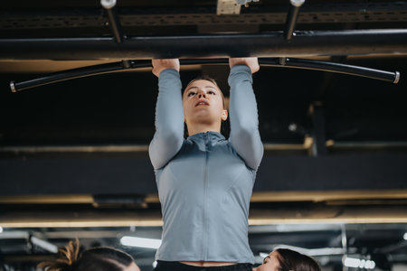 Young Woman Performing Pull-Ups in a Modern Gym Settingの写真素材