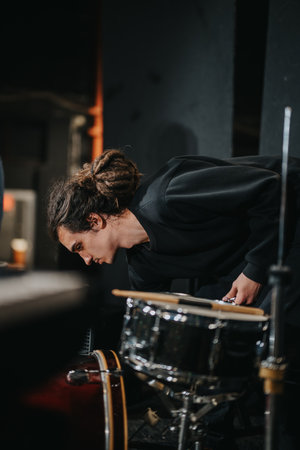 Musician Adjusting Drum Equipment on Stage During Band Setup
