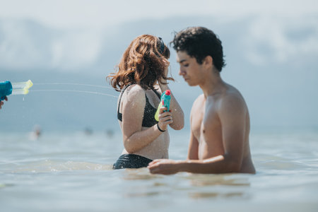 Joyful summer water gun fight at a scenic beach with friendsの写真素材
