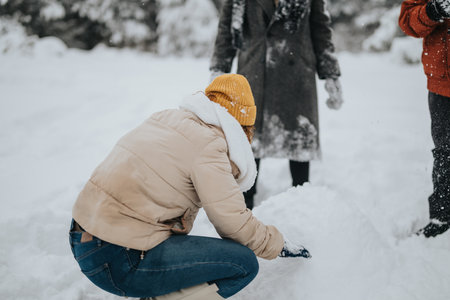 Two people enjoying a snowy day building a snow sculpture outdoorsの写真素材