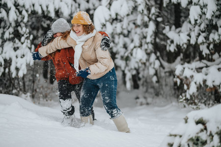 Joyful friends playing in the snow during a winter dayの写真素材