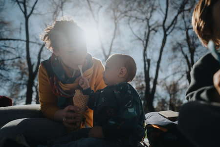 A tender moment between a parent and child enjoying ice cream outdoors on a sunny dayの写真素材