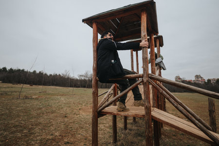 Person climbing a wooden structure in an open grassy outdoor park areaの写真素材
