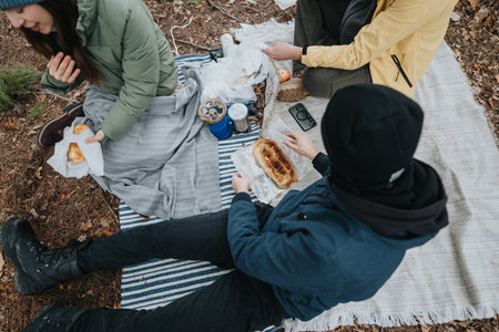 Friends enjoying a picnic in the woods during an autumn outingの写真素材