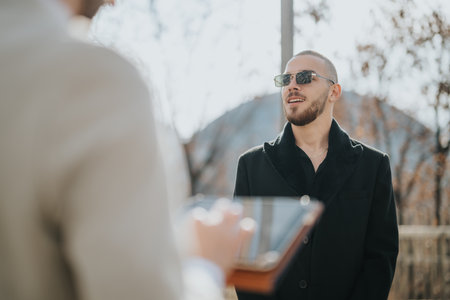 Confident individual speaking outdoors during a professional interaction on a sunny dayの写真素材
