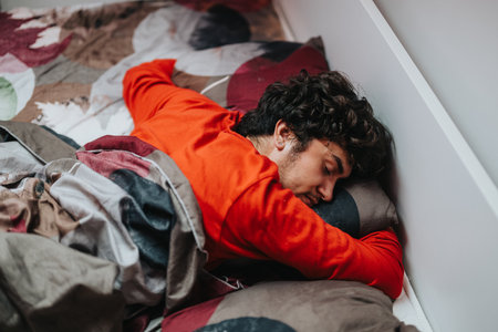 Young man peacefully sleeping in a cozy colorful bed at homeの写真素材