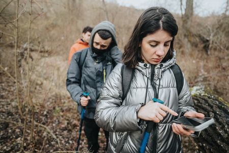 Group of hikers navigating with a smart phone in lush outdoor woodland environmentの写真素材